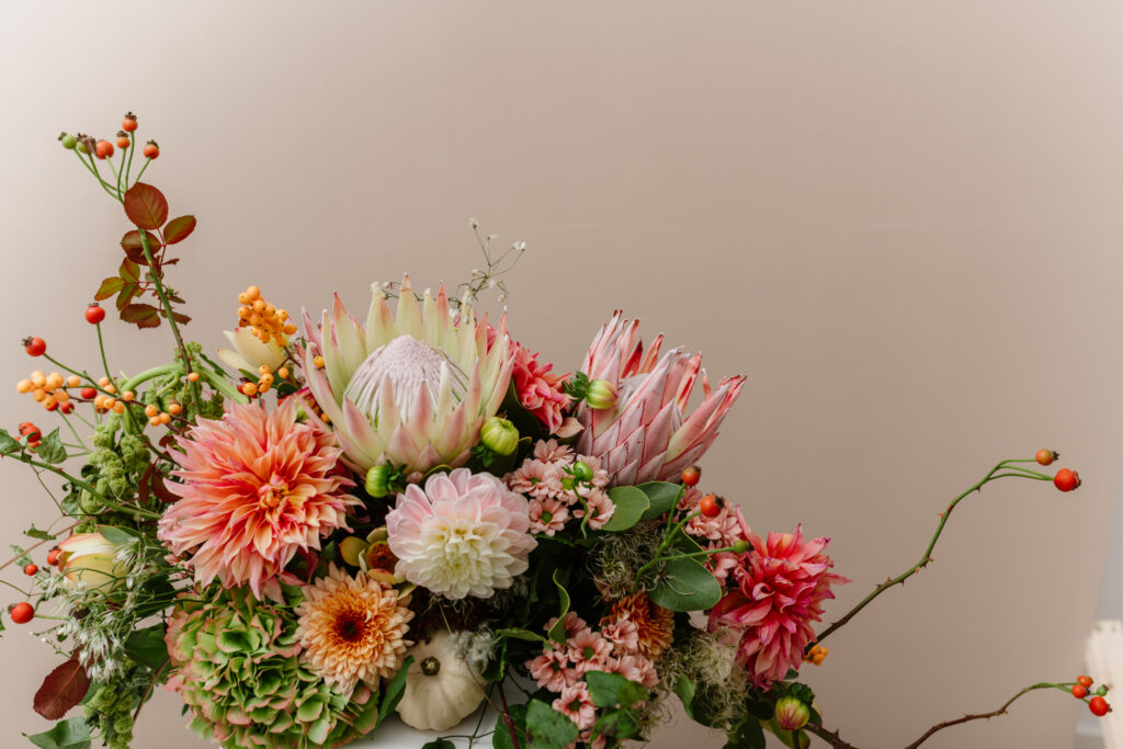 Blumengesteck mit Protea, Dahlien und Hagebutten